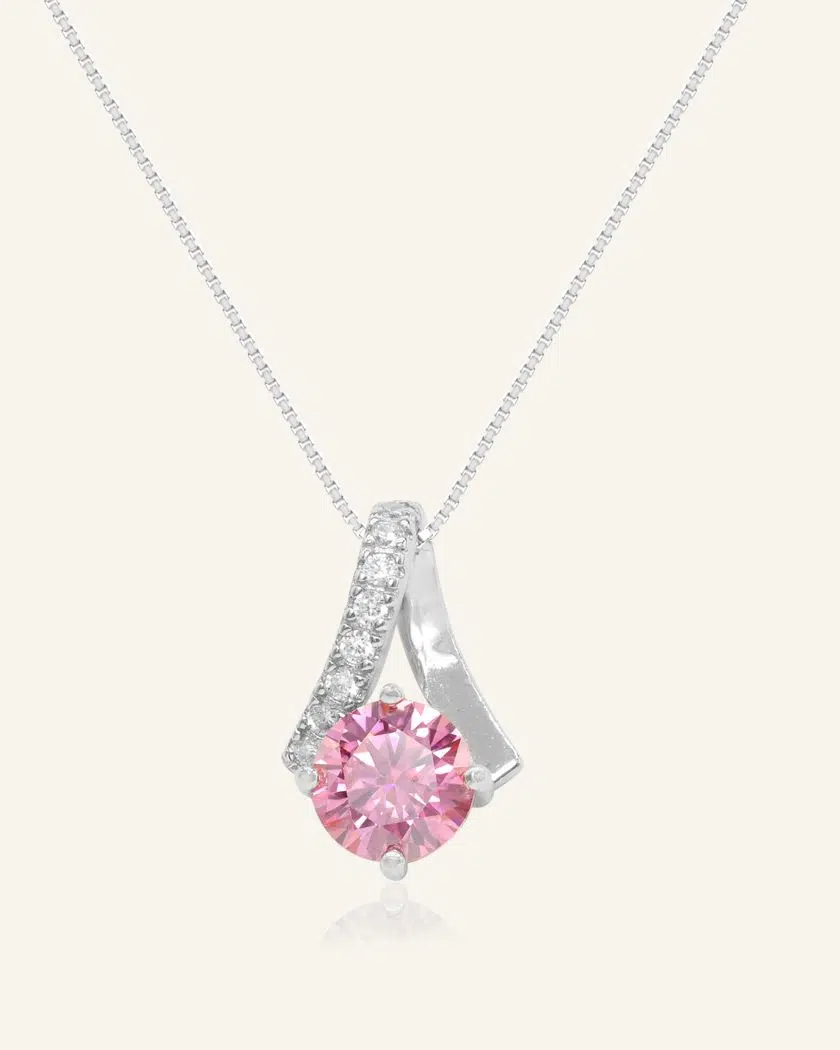 A silver necklace featuring a stunning 1-carat round pink moissanite centerpiece, accented with a graceful curved design adorned with sparkling cubic zirconias.