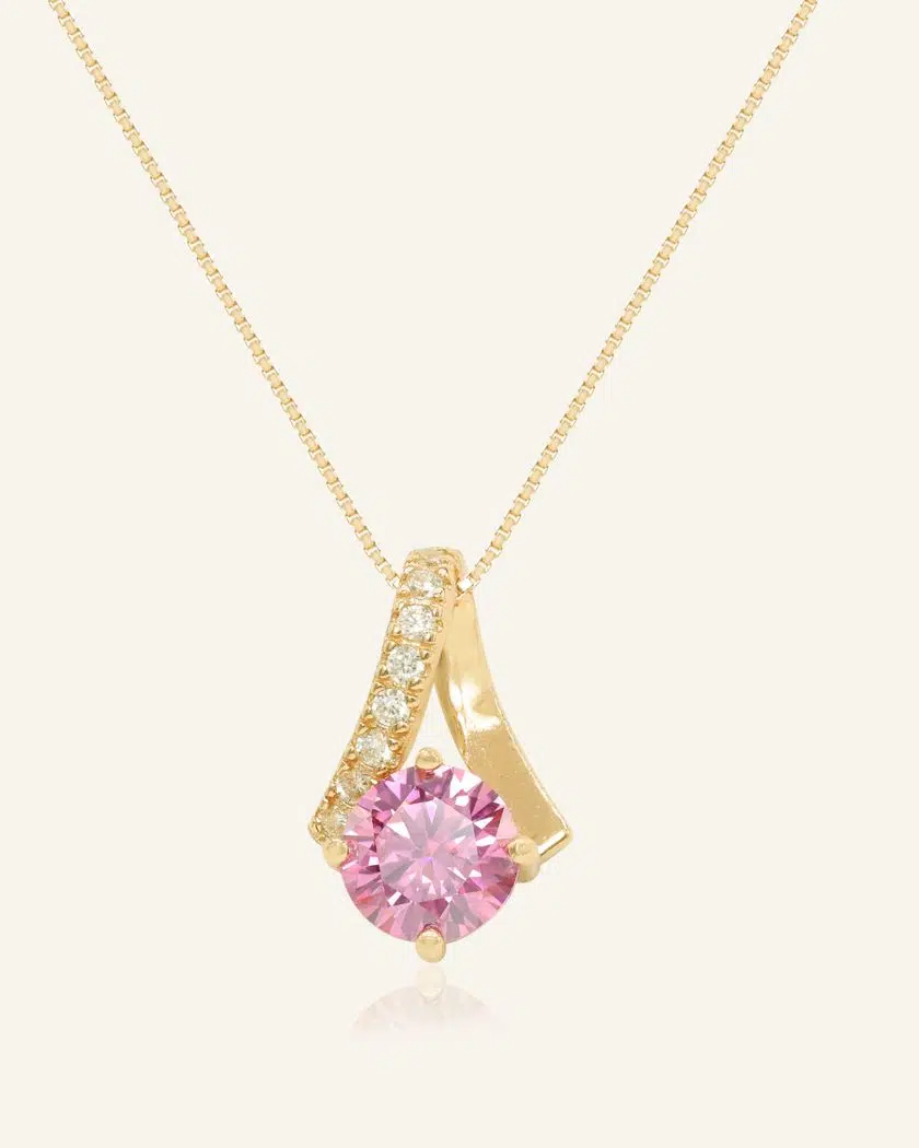A yellow gold necklace featuring a stunning 1-carat round pink moissanite centerpiece, accented with a graceful curved design adorned with sparkling cubic zirconias.