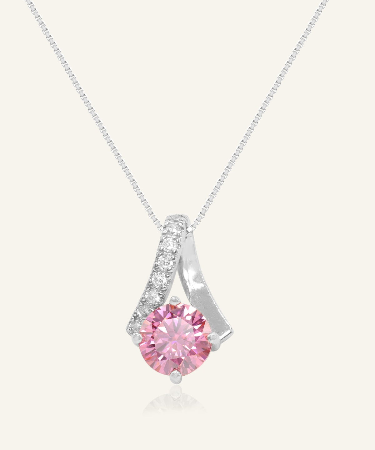1ct Pink Moissanite Necklace in silver, resting on a warm linen background