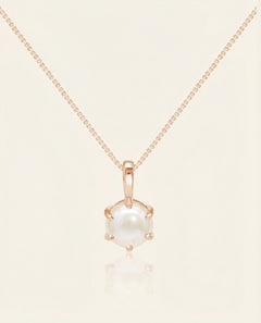Close-up of the Classic Pearl Necklace in rose gold, resting on a warm linen background