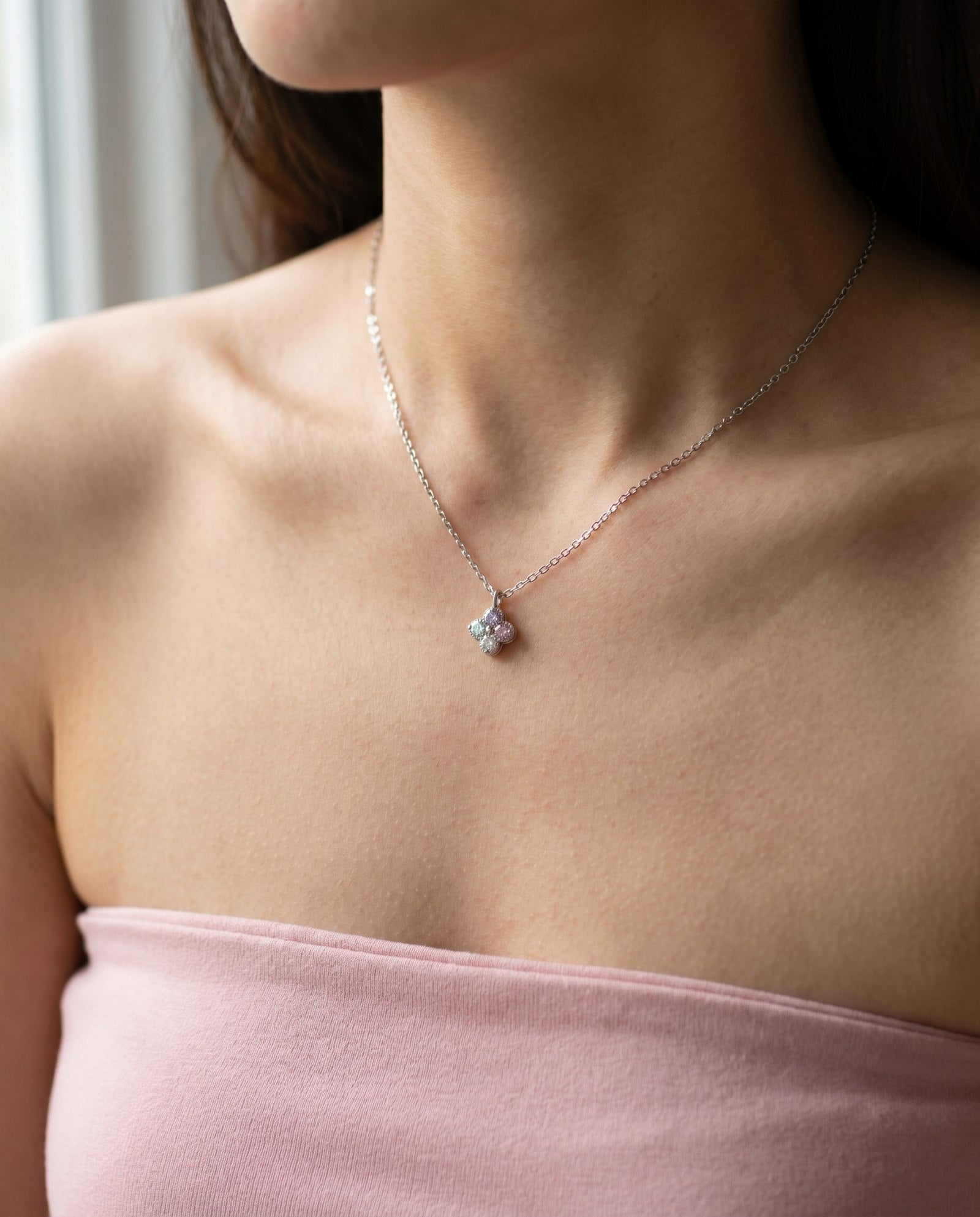 Angled lifestyle shot of the Giverny-inspired clover necklace with sparkling pink, lilac, and mint moissanite.