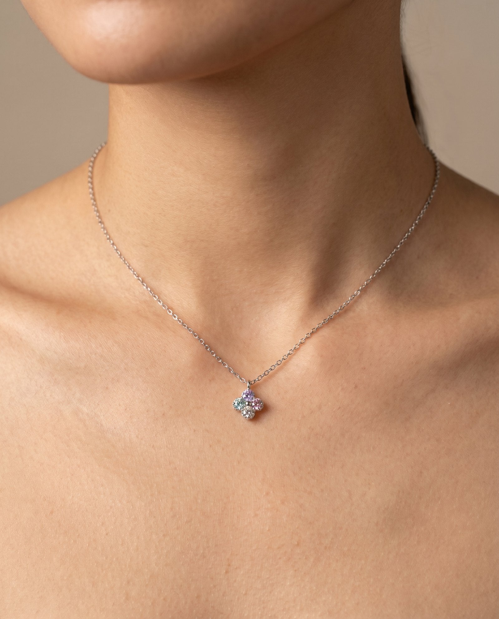 Model wearing the Tale of Two Clovers necklace in silver, showcasing the pastel moissanite side against the skin.