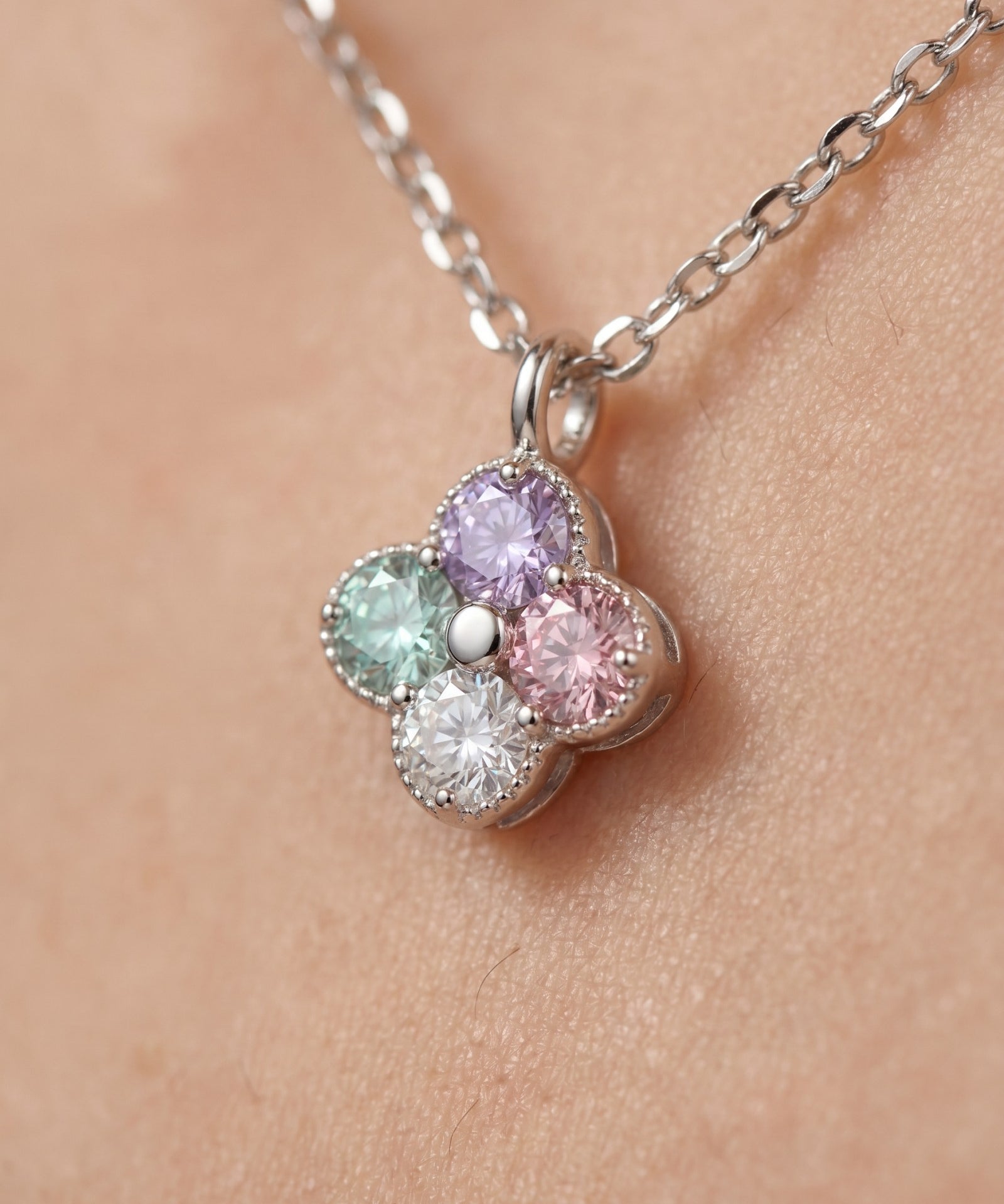 Extreme macro shot of the Tale of Two Clovers necklace, highlighting the hand-set pastel moissanite stones and rhodium-plated silver beads.