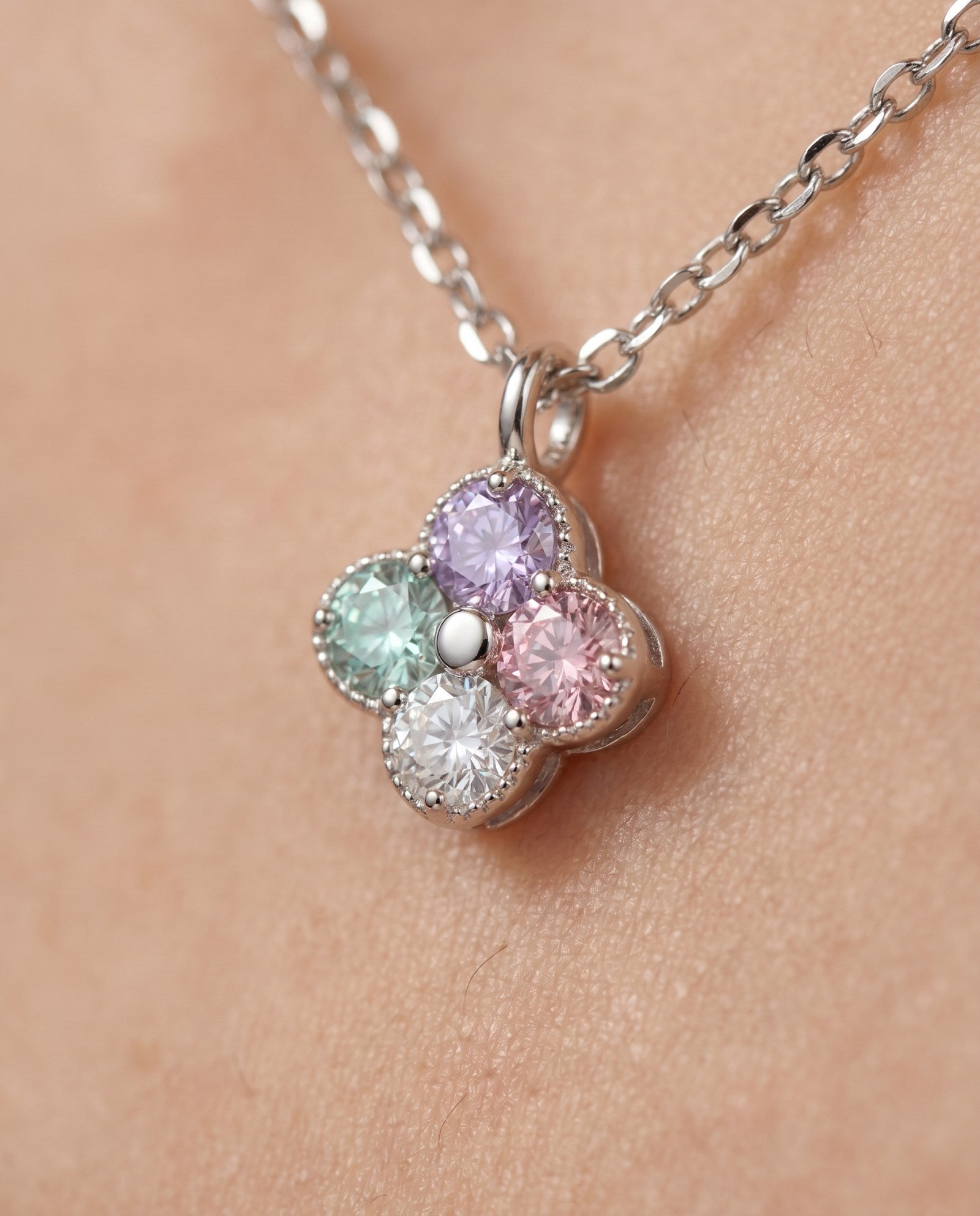 Extreme macro shot of the Tale of Two Clovers necklace, highlighting the hand-set pastel moissanite stones and rhodium-plated silver beads.