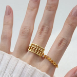 A model wearing the yellow gold abacus ring featuring a rectangular frame with golden beads and yellow citrine stones, designed to mimic a traditional abacus, adding a playful and unique touch to your jewelry collection.