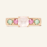 A rose gold ring featuring a central square-cut rose quartz stone, flanked by two pink tourmaline and two green moissanites on either side, set in a textured band.