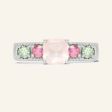 A silver ring featuring a central square-cut rose quartz stone, flanked by two pink tourmaline and two green moissanites on either side, set in a textured band.