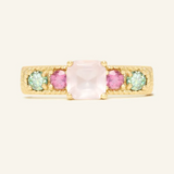 A yellow goldring featuring a central square-cut rose quartz stone, flanked by two pink tourmaline and two green moissanites on either side, set in a textured band.