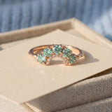 Arc Green Moissanite Ring in rose gold, laid flat on a tabletop