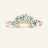 Arc Green Moissanite Ring in rose gold, resting on a warm linen background
