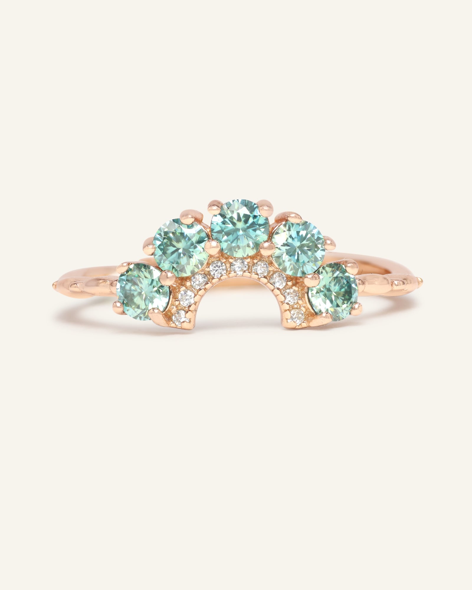 Arc Green Moissanite Ring in rose gold, resting on a warm linen background