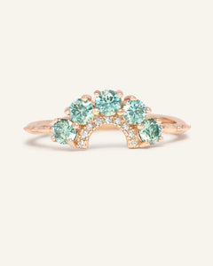 Arc Green Moissanite Ring in rose gold, resting on a warm linen background