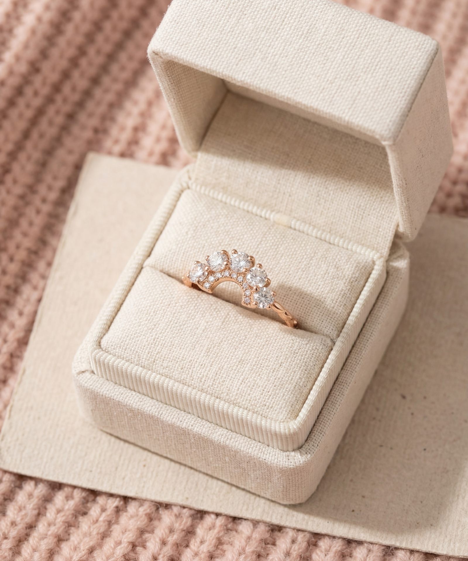 Arc White Moissanite Ring in rose gold, laid flat on a tabletop