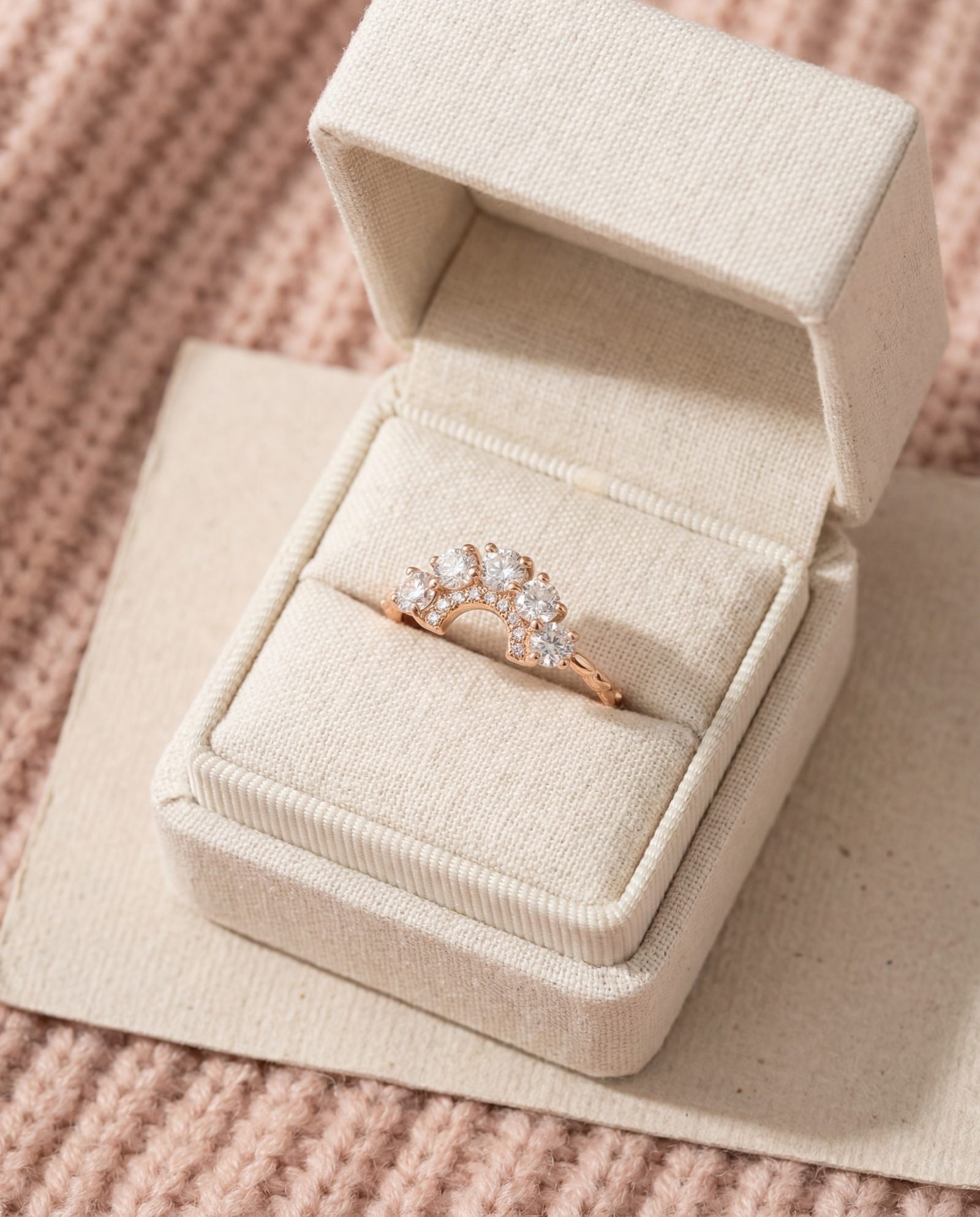Arc White Moissanite Ring in rose gold, laid flat on a tabletop
