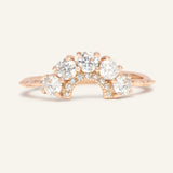 Arc White Moissanite Ring in rose gold, resting on a warm linen background