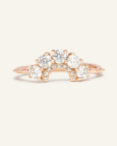 Arc White Moissanite Ring in rose gold, resting on a warm linen background