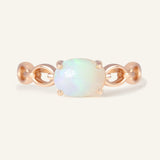 Close-up of the Astra Opal Ring in rose gold, resting on a warm linen background