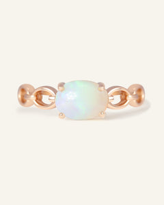 Close-up of the Astra Opal Ring in rose gold, resting on a warm linen background