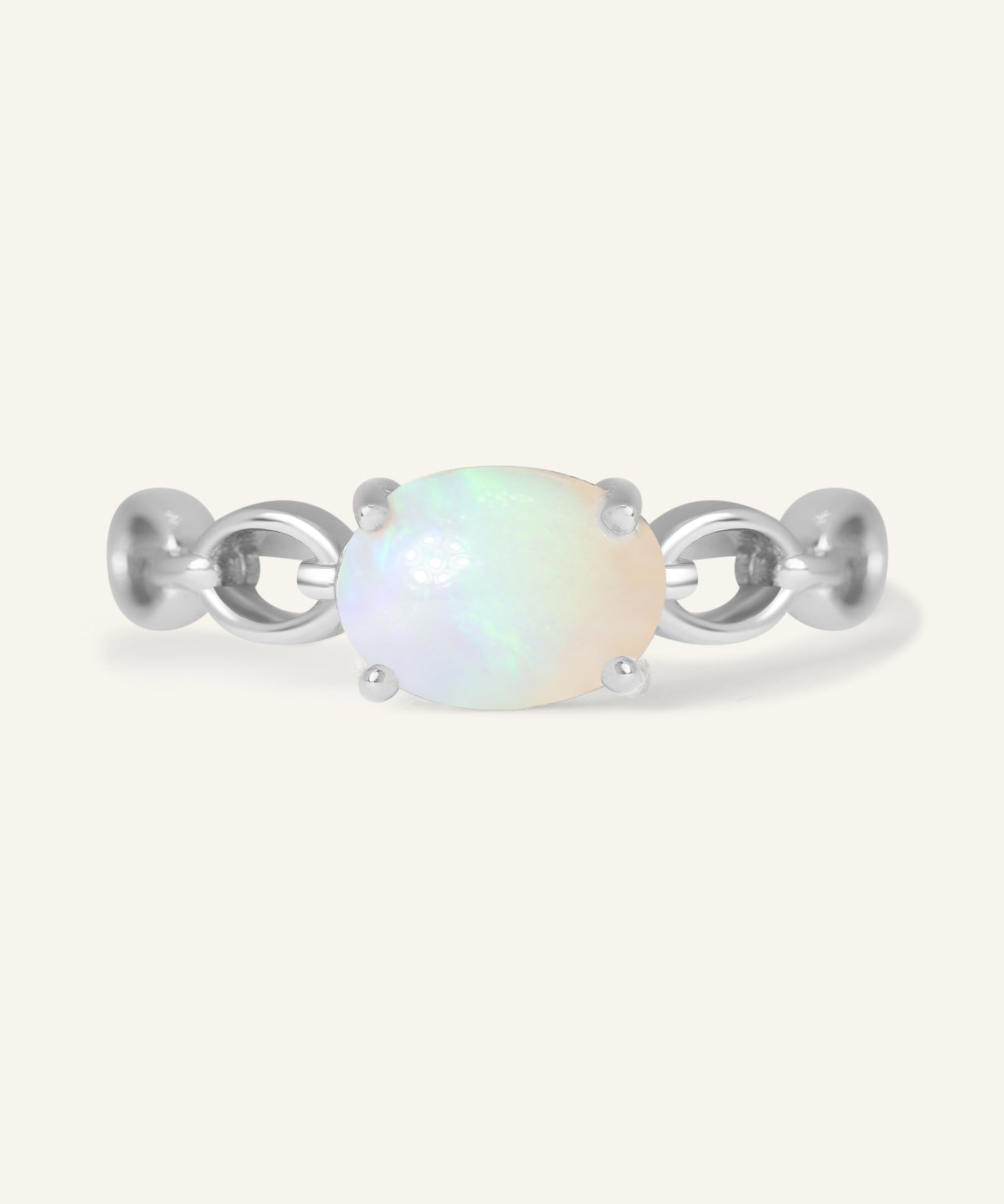 Astra Opal Ring in silver, resting on a warm linen background