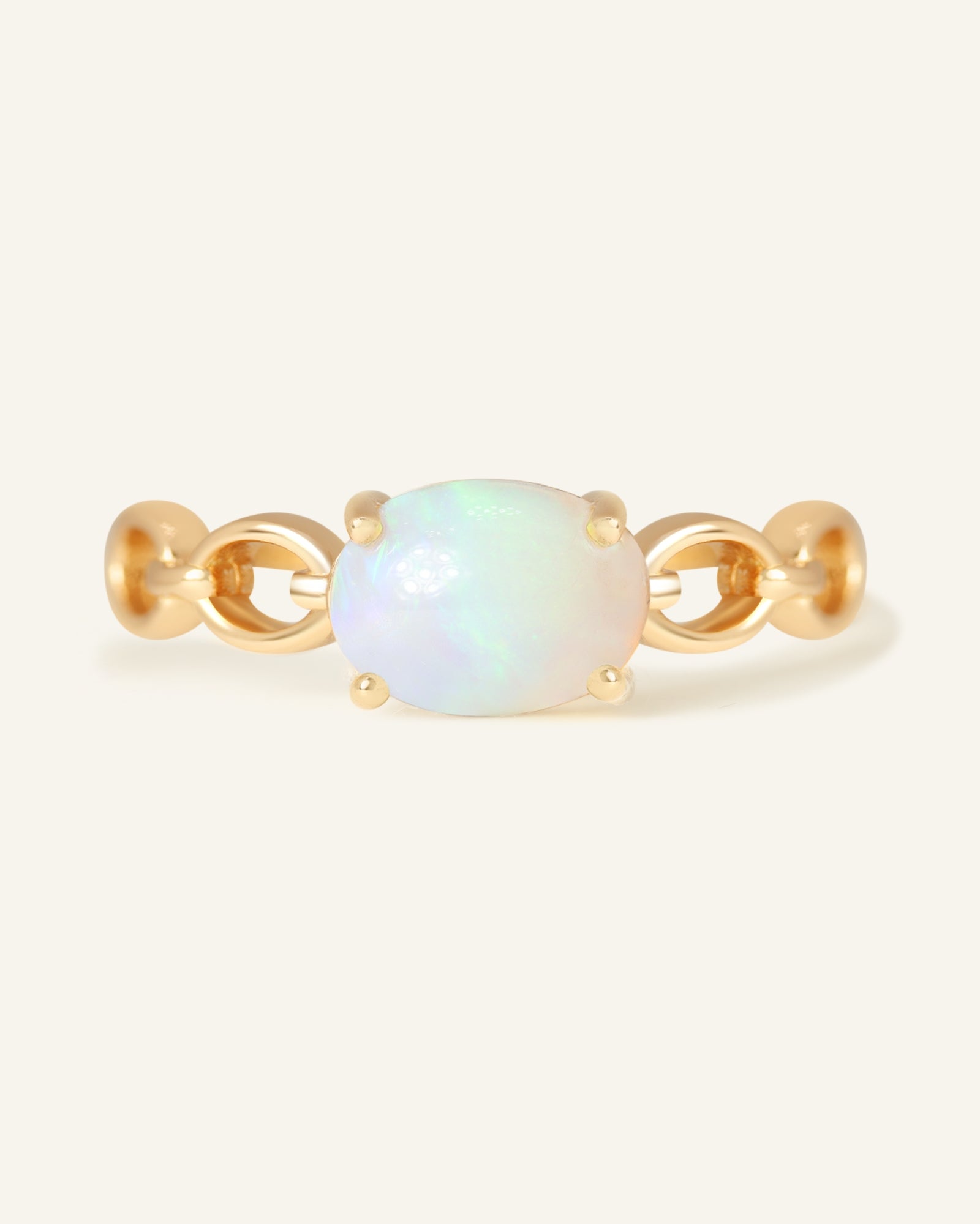 Astra Opal Ring in yellow gold, resting on a warm linen background