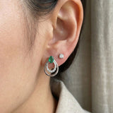 Direct on-ear view of Aura Emerald Drop Studs in silver, showing the delicate scale and "nested" frame detail.