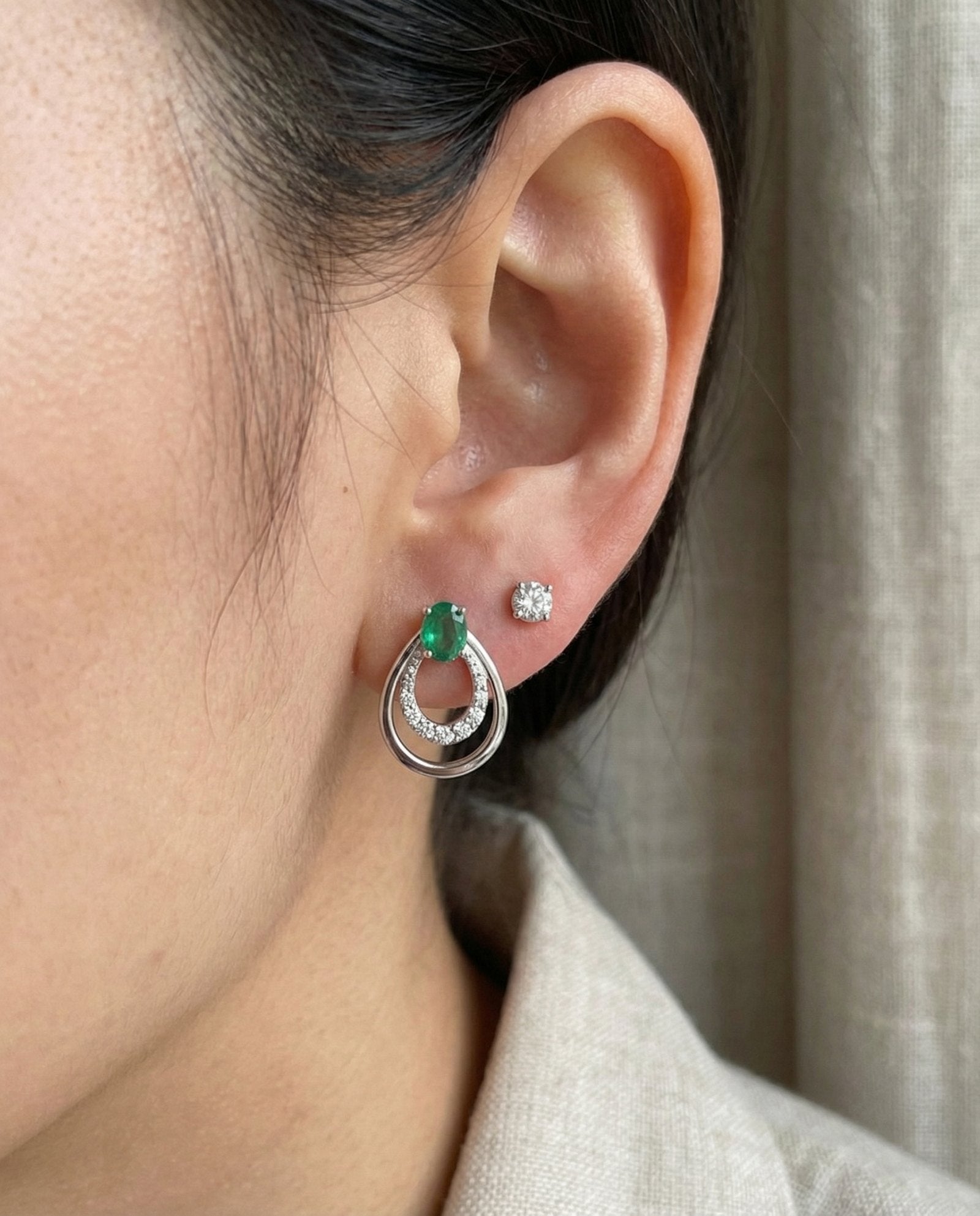 Direct on-ear view of Aura Emerald Drop Studs in silver, showing the delicate scale and "nested" frame detail.