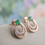 Macro view of the Aura Emerald Drop Studs in 18k Rose Gold showing the natural oval emerald and shimmering pavé halo.