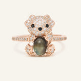 Black Sunstone Koala Bear Ring in rose gold, resting on a warm linen background