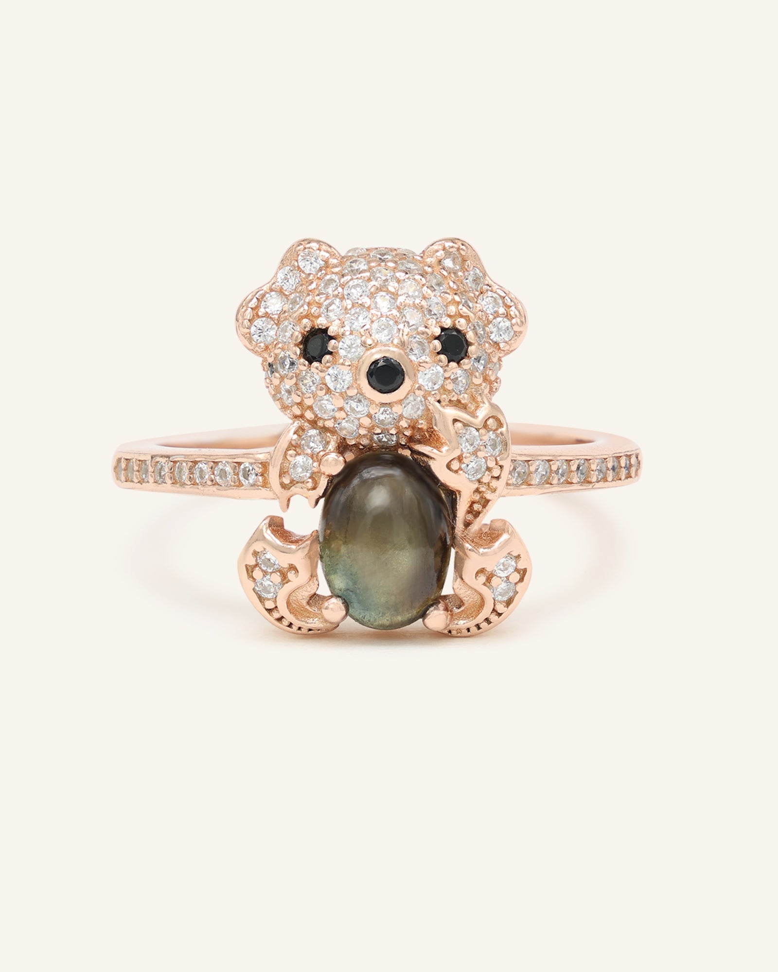 Black Sunstone Koala Bear Ring in rose gold, resting on a warm linen background