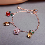 Rose gold slider bracelet featuring whimsical charms including a pineapple, orange, flower with pearl, and golden ingot, symbolizing blessings, wealth and joy.