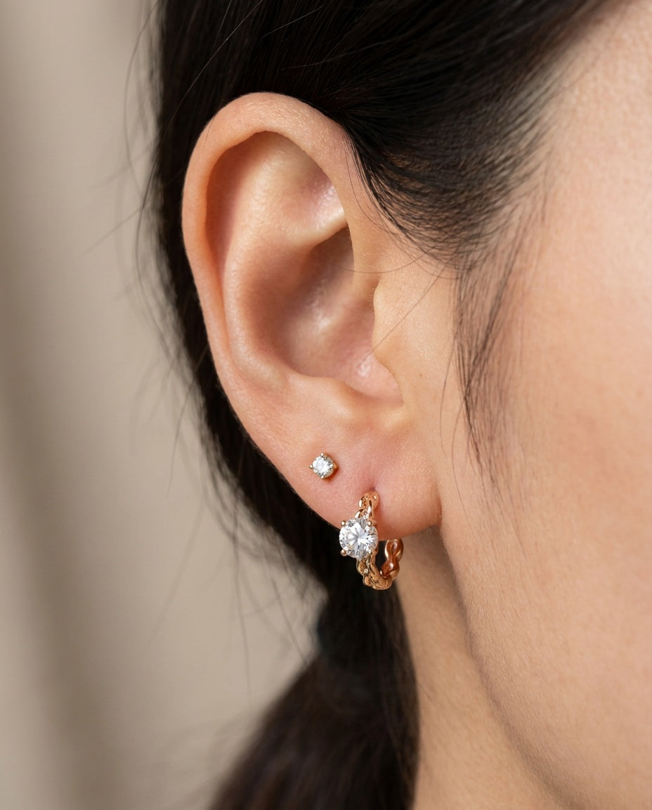 Model wearing a rose gold vermeil Braided White Moissanite Huggie Hoop paired with a second lobe stud.