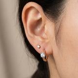 Model wearing a rose gold vermeil Braided White Moissanite Huggie Hoop paired with a second lobe stud.
