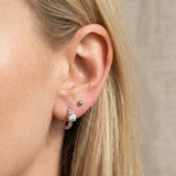 Blonde model wearing a silver Braided White Moissanite Huggie Hoop on the main lobe piering.