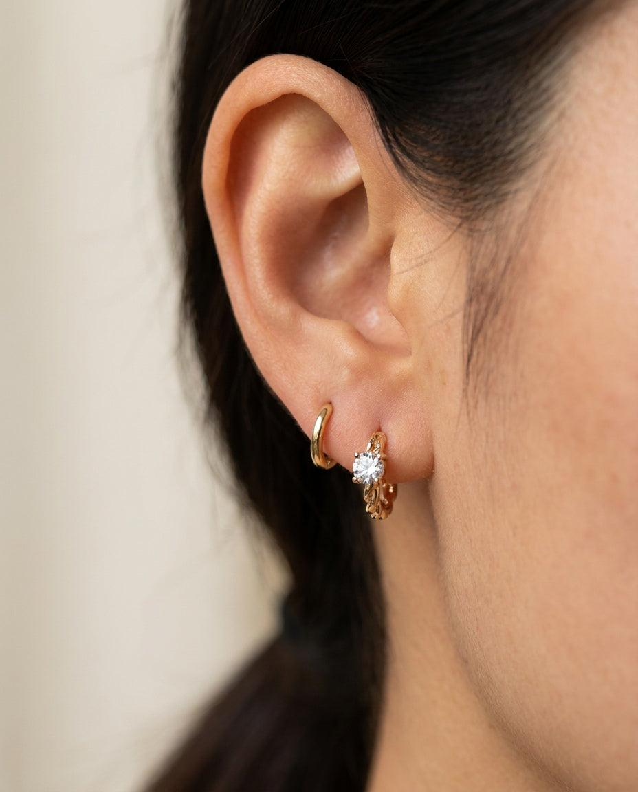 Side profile shot of a model wearing a yellow gold Braided White Moissanite Huggie Hoop stacked with a plain gold huggie.