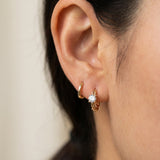 Side profile shot of a model wearing a yellow gold Braided White Moissanite Huggie Hoop stacked with a plain gold huggie.
