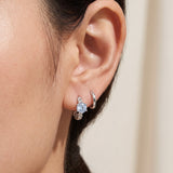 Close-up of a blonde model wearing a rose gold vermeil Braided Sky Blue Moissanite Huggie Hoop stacked with a small gold hoop and stud.