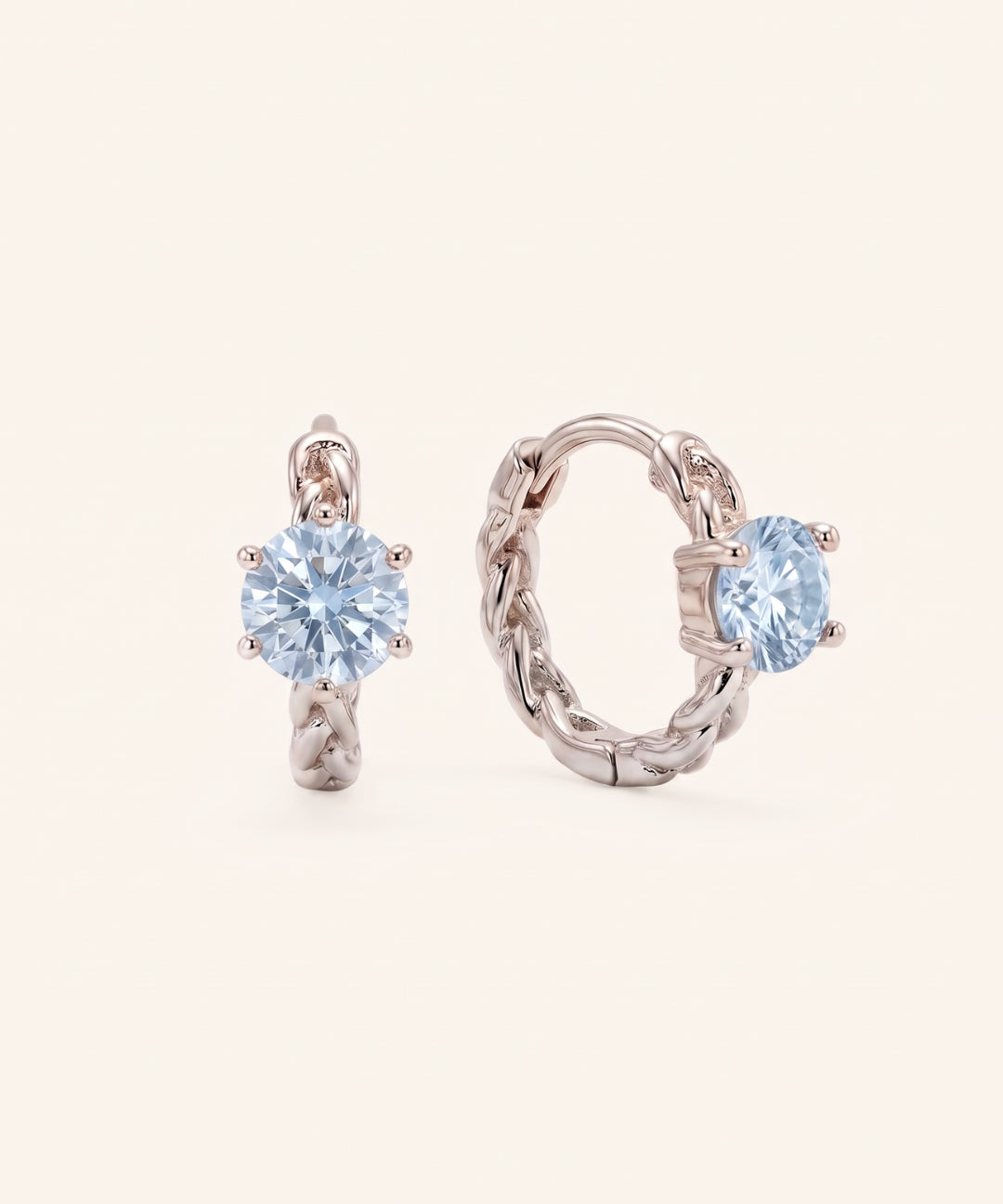 Pair of sterling silver Braided Sky Blue Moissanite Huggie Hoops featuring 0.5ct round light blue moissanite solitaire stones.