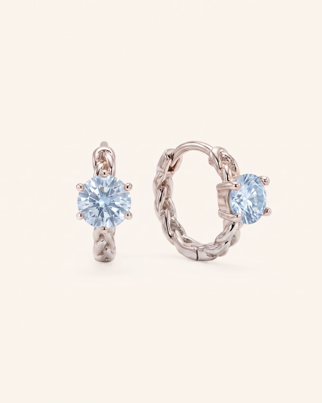 Pair of sterling silver Braided Sky Blue Moissanite Huggie Hoops featuring 0.5ct round light blue moissanite solitaire stones.