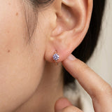 Side profile shot of a model wearing a rose gold vermeil Braided Lavender Moissanite Huggie Hoop (1ctw) with a finger touching the ear.