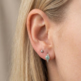 Blonde model wearing a sterling silver Braided Mint Moissanite Huggie Hoop in the main lobe piercing.