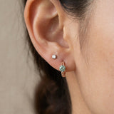 Model wearing a rose gold vermeil Braided Mint Moissanite Huggie Hoop paired with a single solitaire lobe stud.
