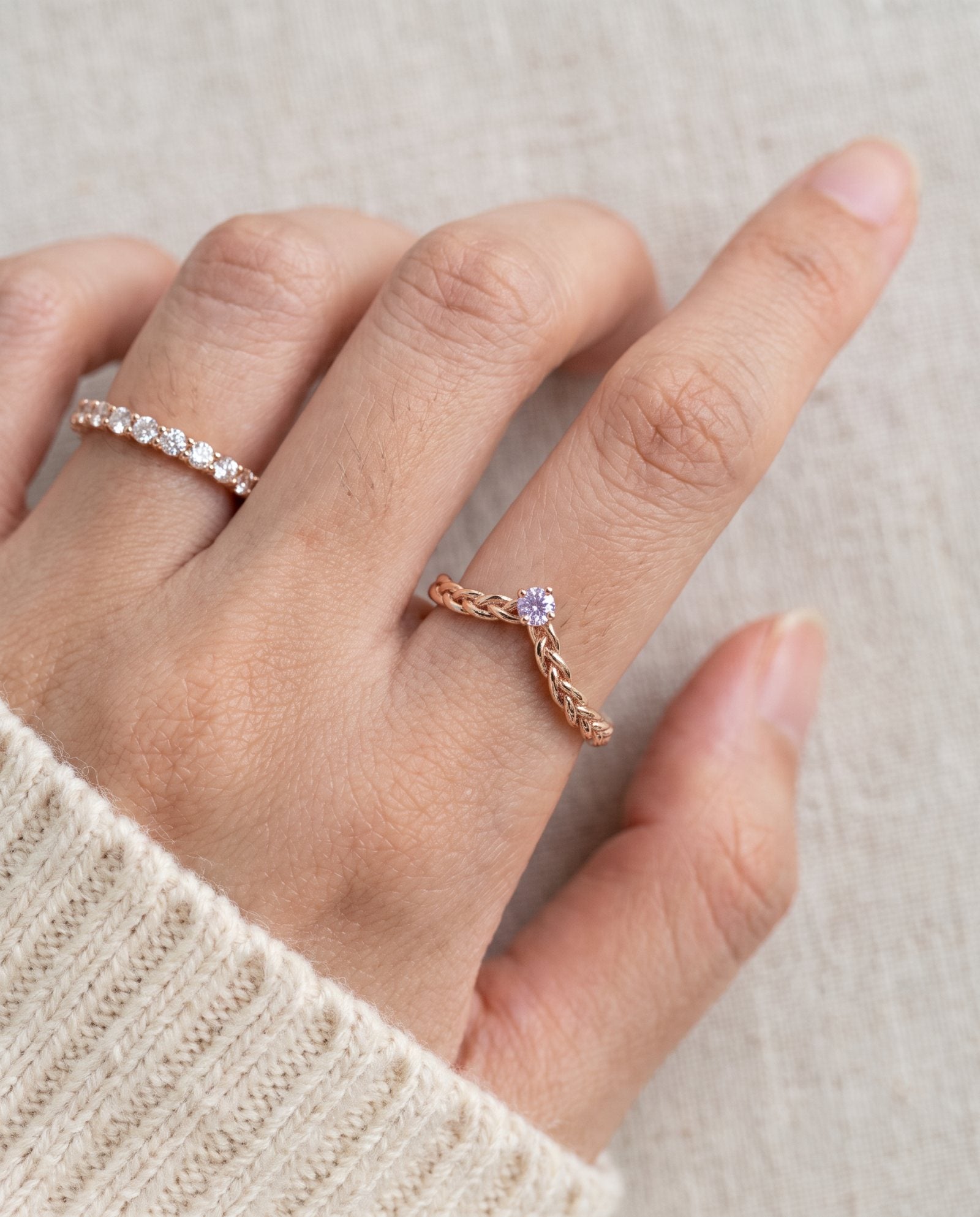 Model wearing a rose gold vermeil Braided Wishbone Lavender Moissanite Ring worn solo on index finger.