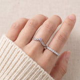 Model wearing a sterling silver Braided Wishbone Lavender Moissanite Ring stacked alongside a thin pave band.
