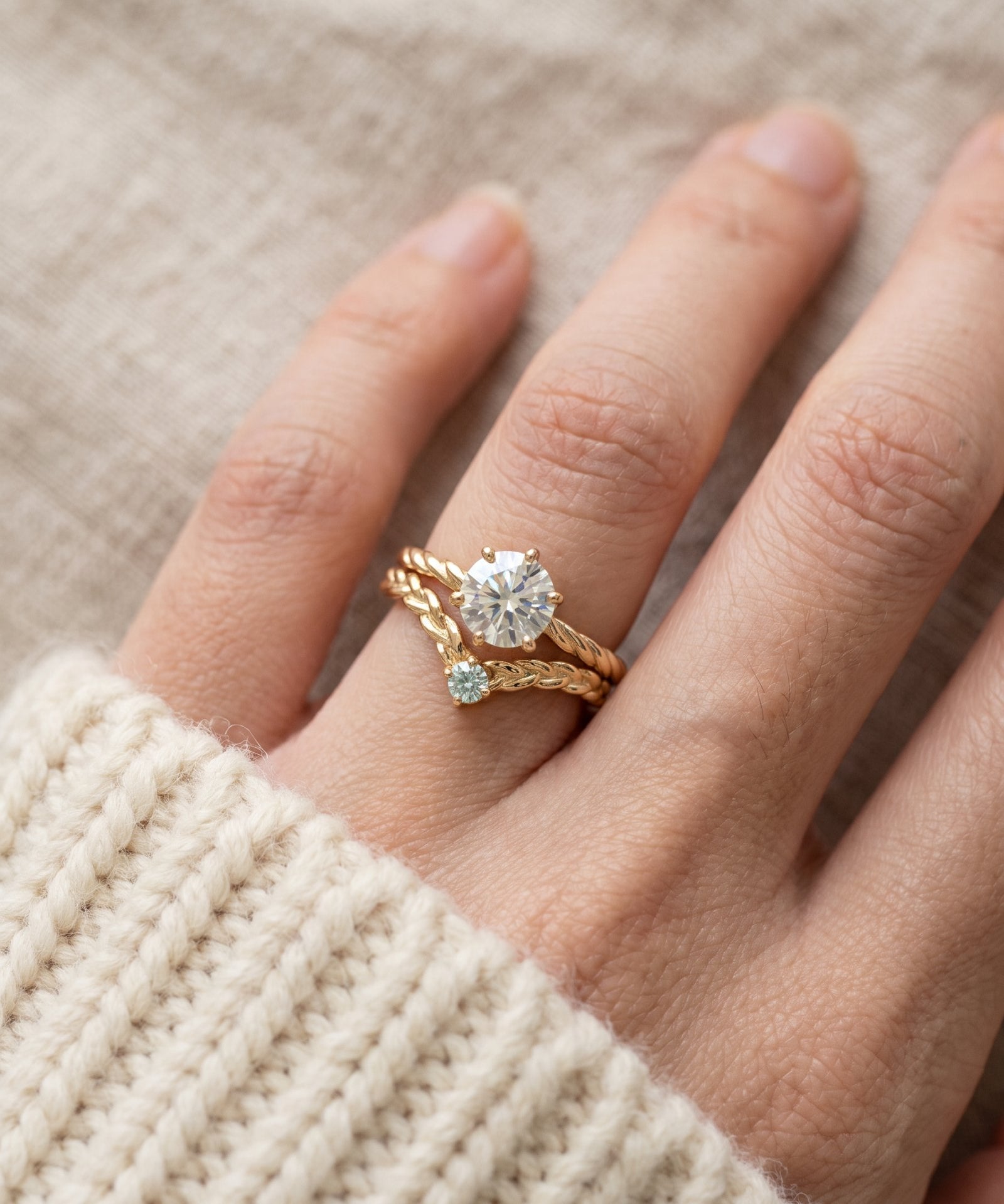Model wearing a yellow gold Braided Wishbone Mint Moissanite Ring stacked below a one carat diamond ring.