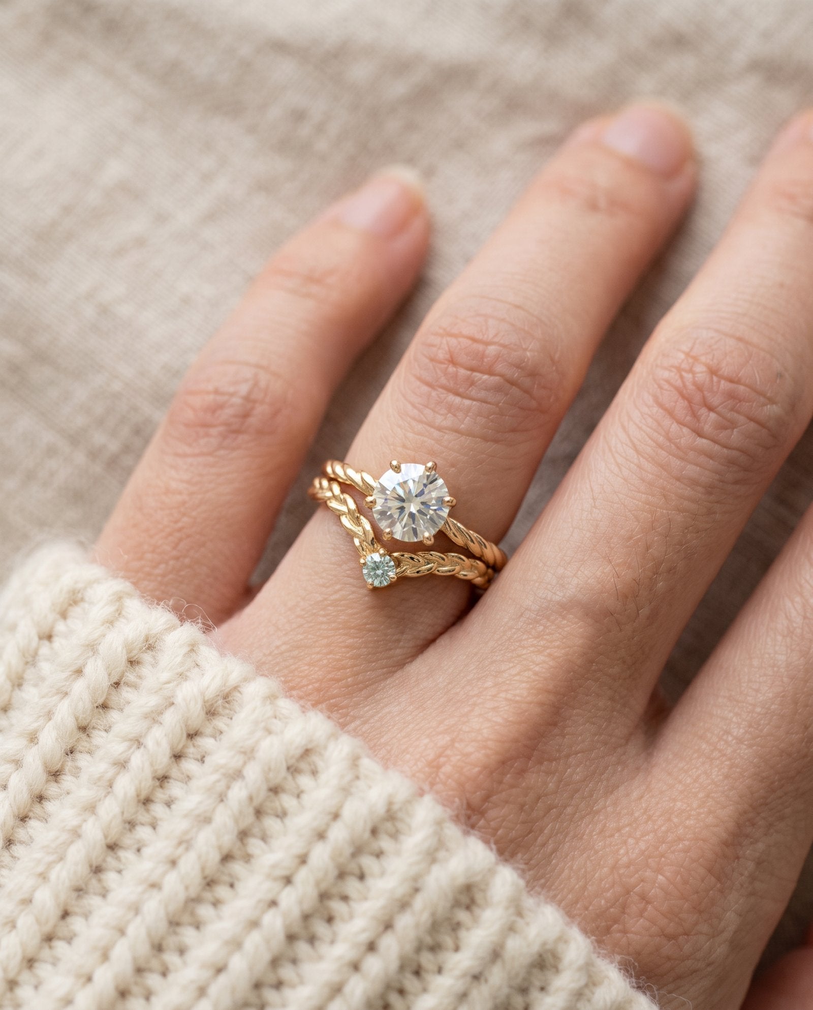 Model wearing a yellow gold Braided Wishbone Mint Moissanite Ring stacked below a one carat diamond ring.