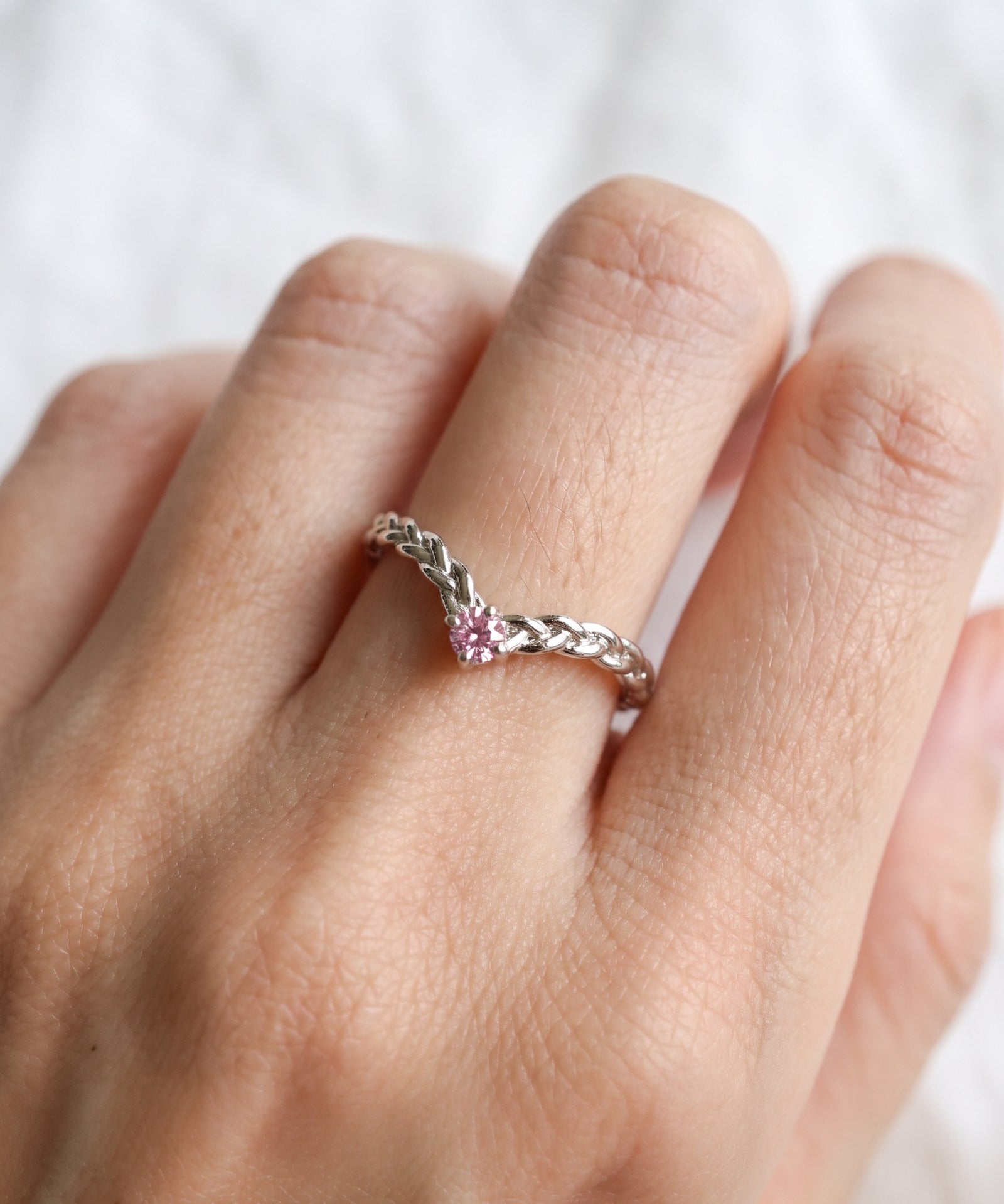 Model wearing a sterling silver Braided Wishbone Pink Moissanite Ring worn solo on index finger.