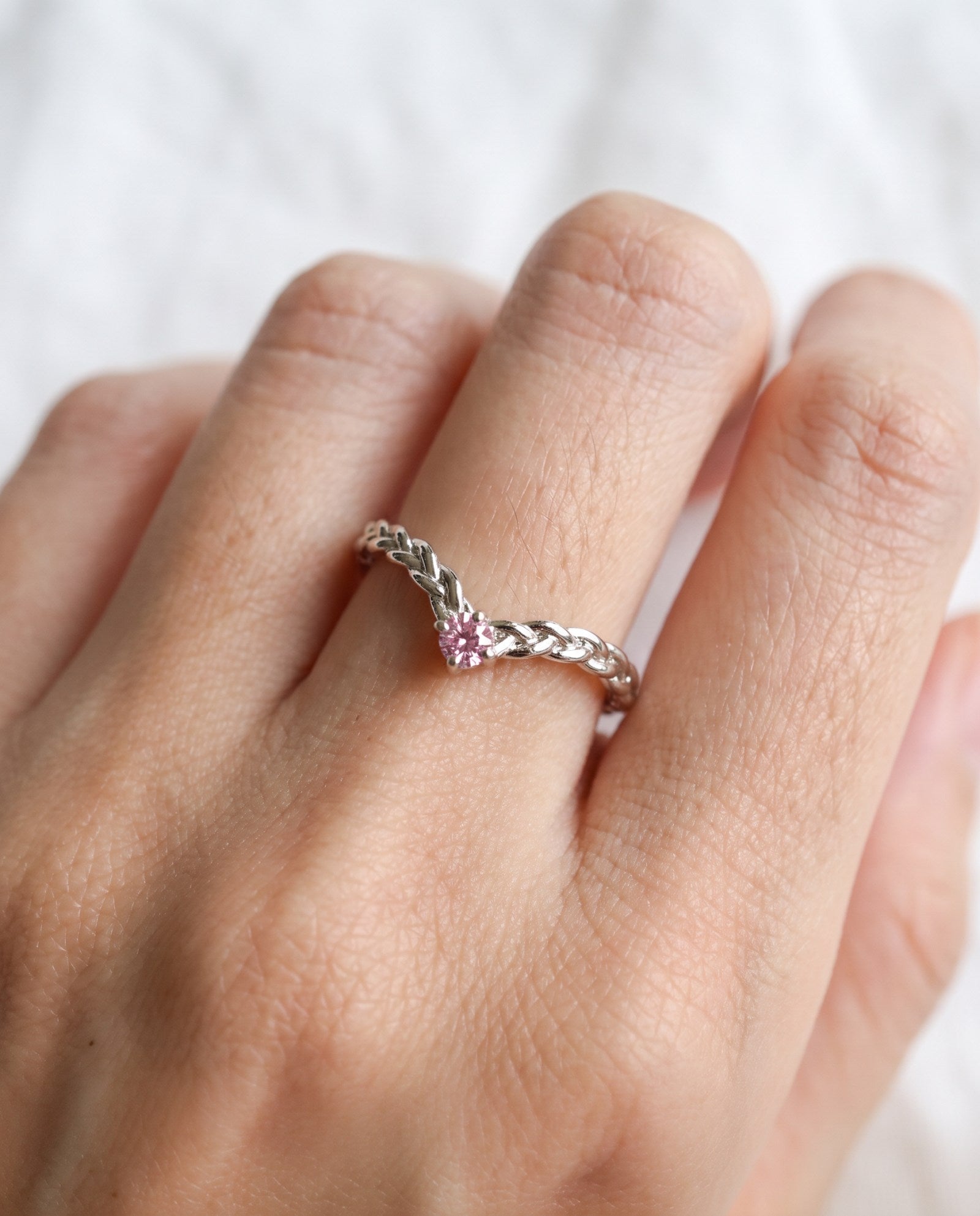Model wearing a sterling silver Braided Wishbone Pink Moissanite Ring worn solo on index finger.