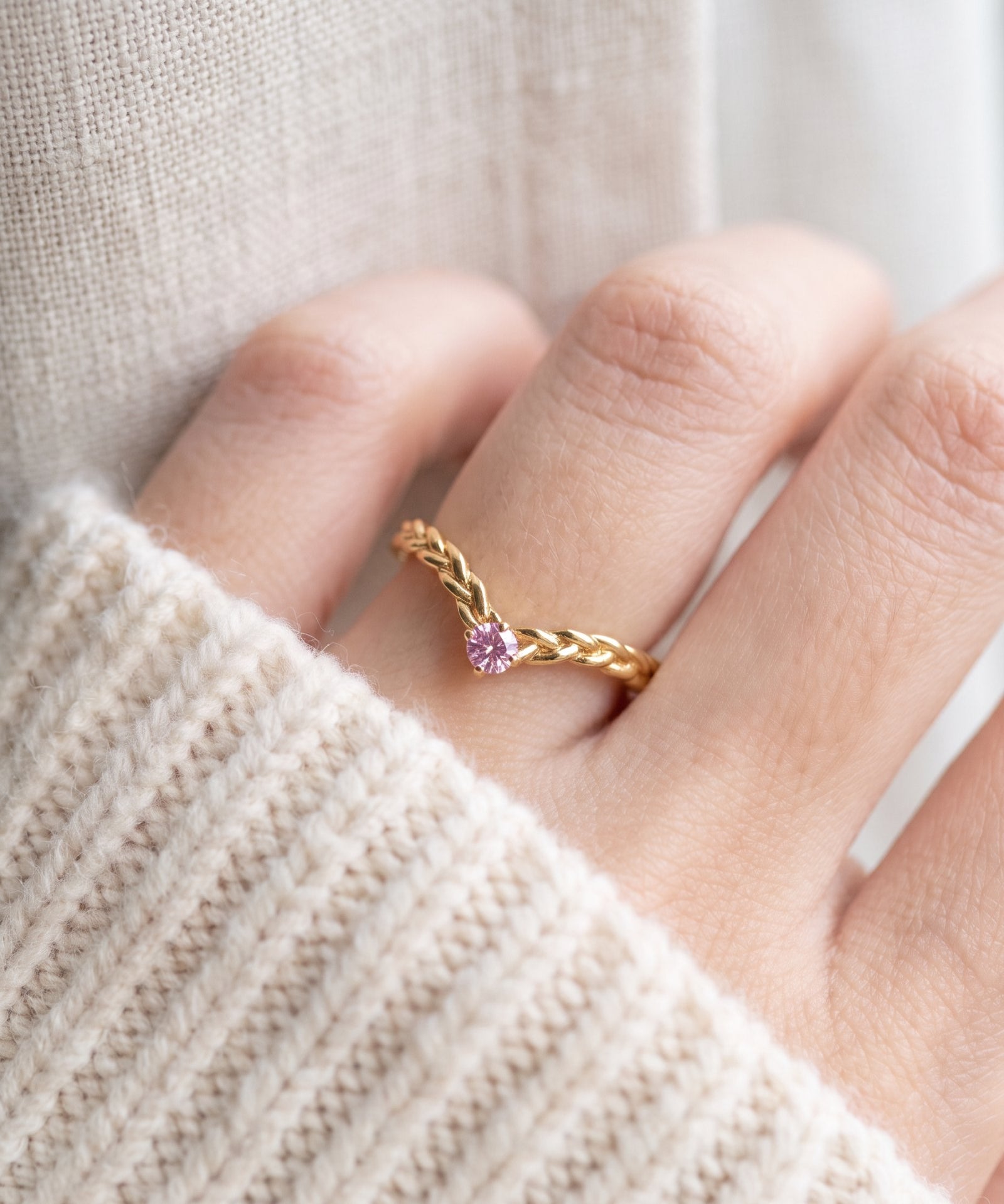Model wearing a yellow gold vermeil Braided Wishbone Pink Moissanite Ring worn solo on index finger.