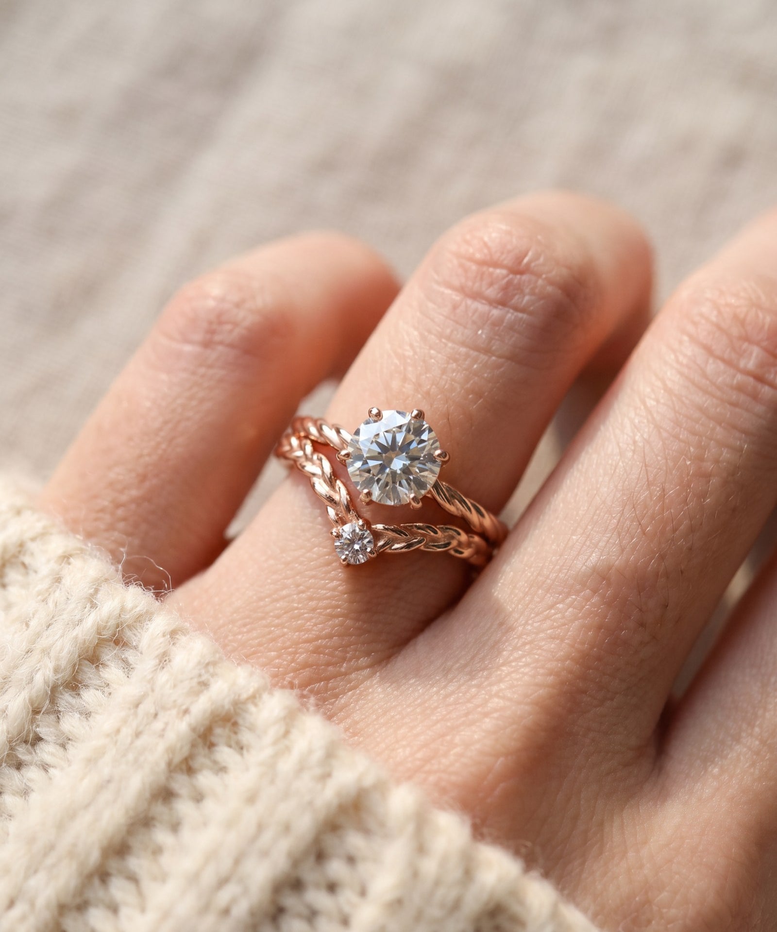 Model wearing a rose gold Braided Wishbone White Moissanite Ring stacked below a large round solitaire engagement ring.