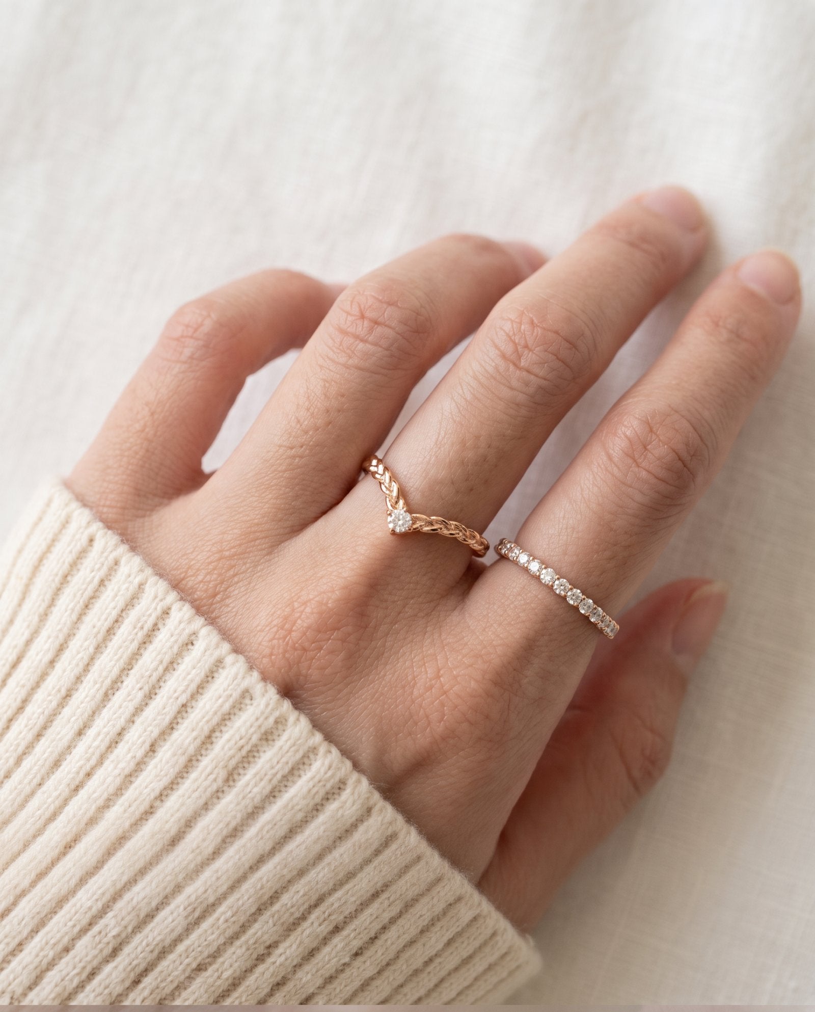 Model wearing a rose gold vermeil Braided Wishbone White Moissanite Ring on middle finger alongside a delicate eternity band.